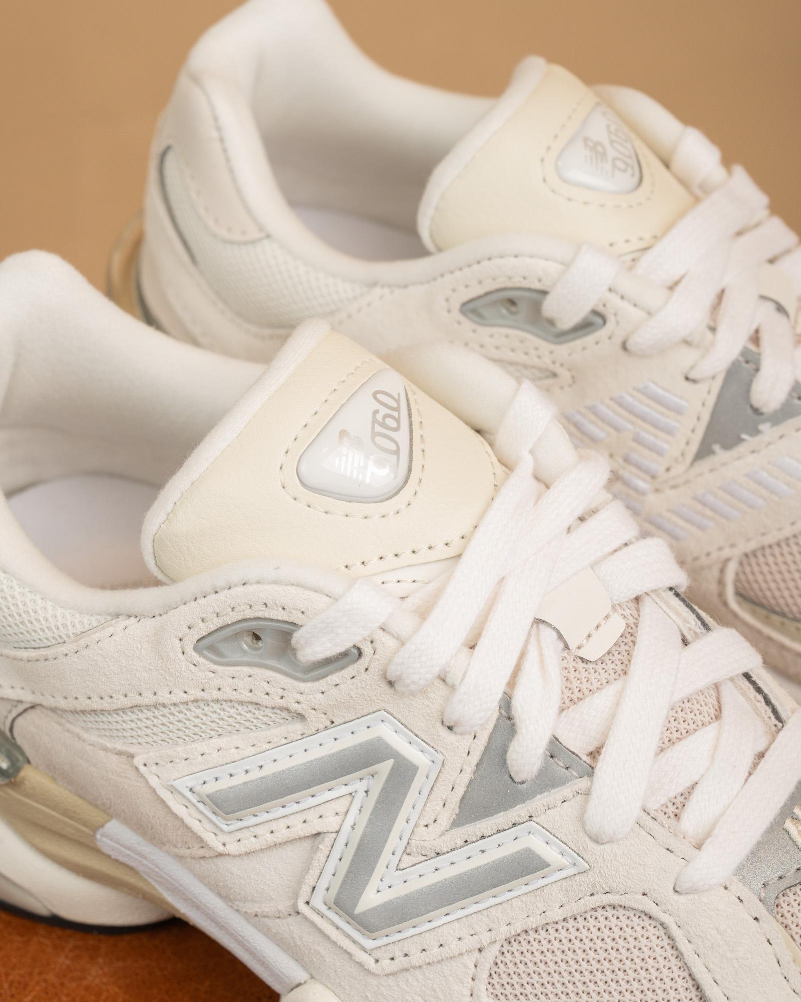 Primo piano del logo New Balance "N" e dei pannelli in suede color crema delle 9060 Sea Salt, sneakers design futuristico.