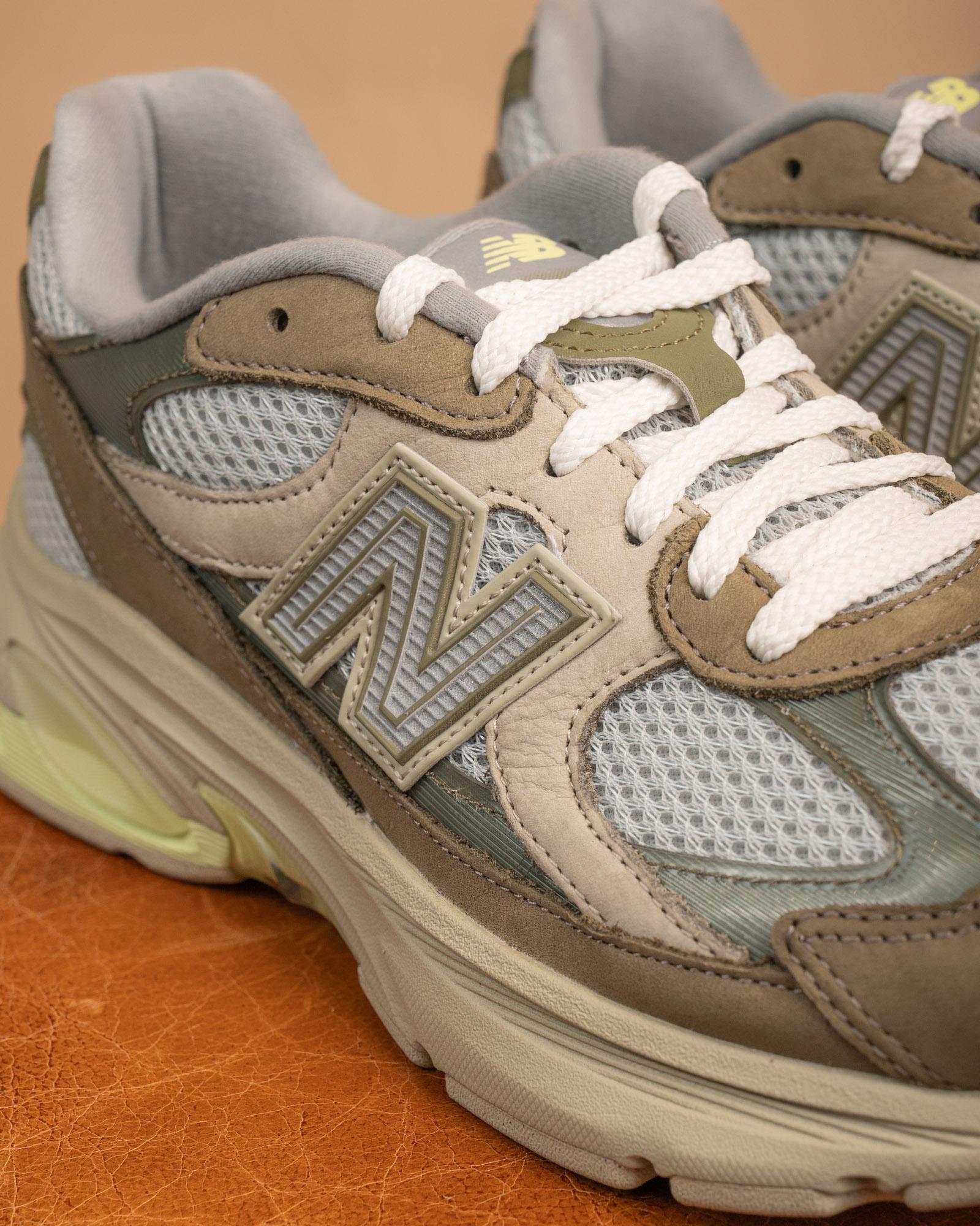 Dettaglio dell'intersuola segmentata ABZORB e del logo N delle New Balance 2010, sneakers tecniche in verde e lime.