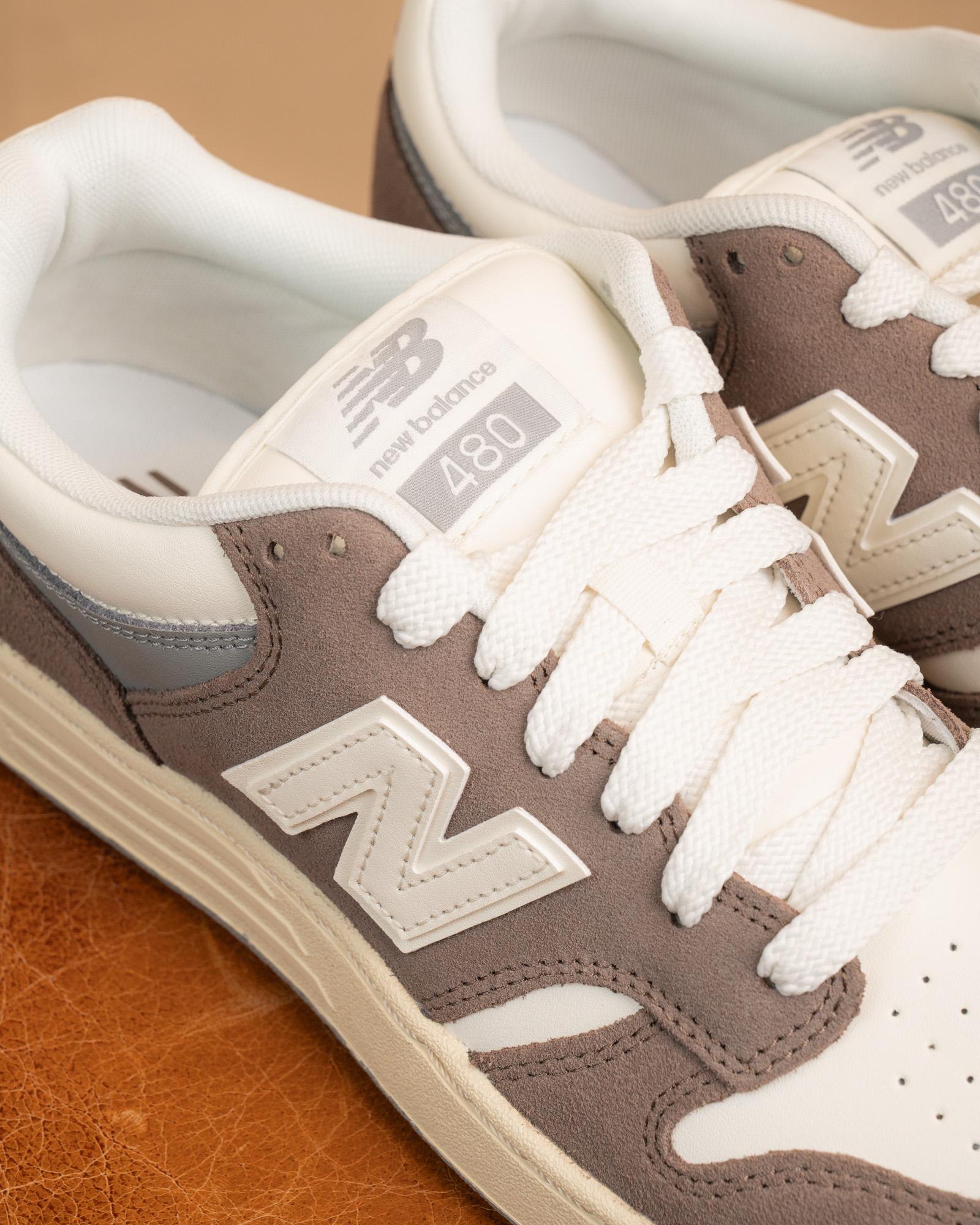 Primo piano del logo New Balance marrone scuro su tomaia in pelle color panna delle NB 480 Cortado.