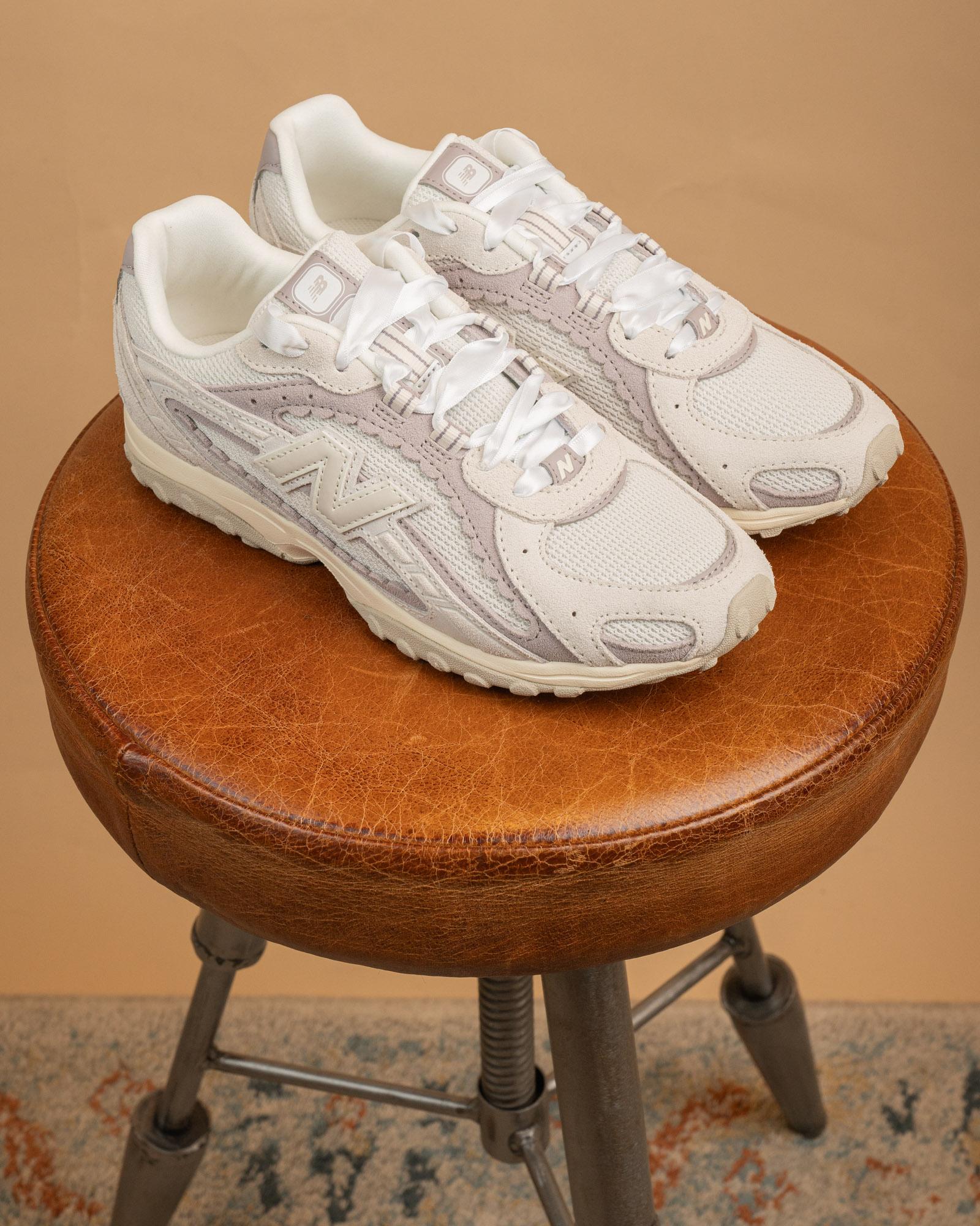 Sneakers New Balance 204 in pelle off-white con logo N e dettagli color lilla pastello su tallone e linguetta.